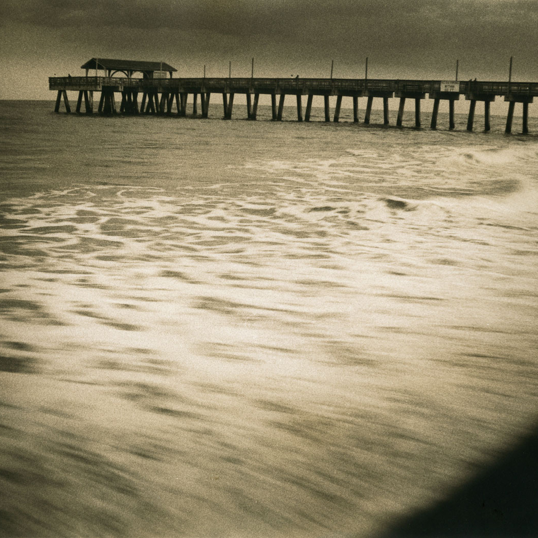 black and white tybee island pier as the tide comes in